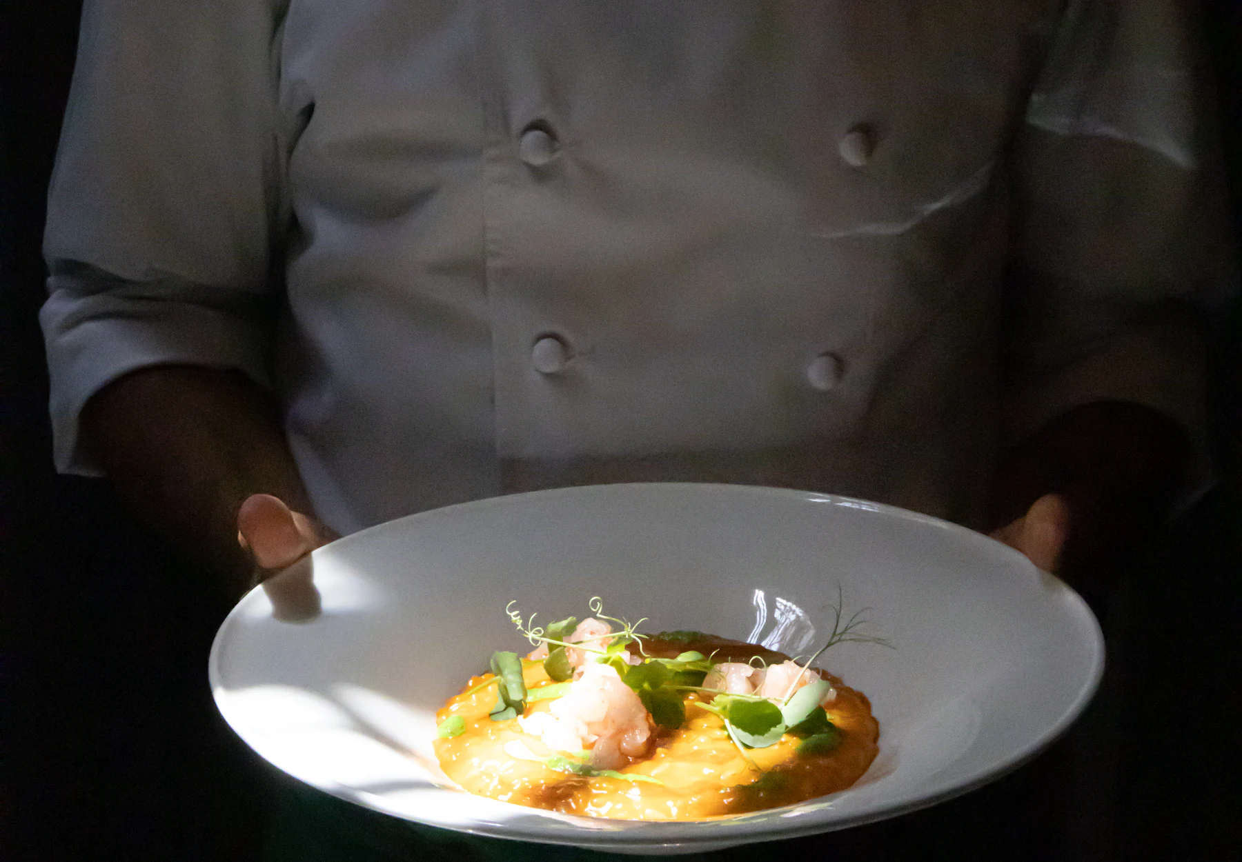 Plato gourmet de Burako Gourmet servido en la mesa, con el restaurante desenfocado de fondo